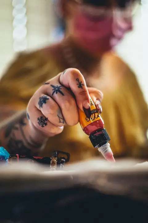 Tattooed hand squeezing a bottle of ink