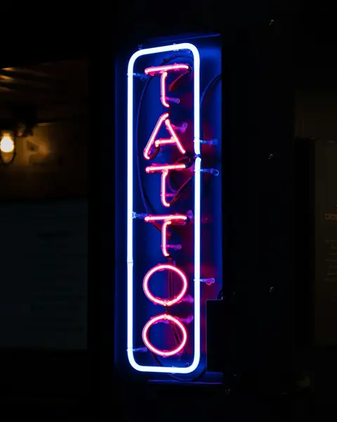 Vertical neon sign that reads TATTOO