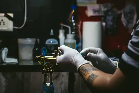 Gloved hands setting up a coil machine at a studio bench